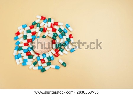 Human brain model surrounded by colorful capsules on yellow background, representing brain medication, mental health treatment, neurology, pharmacy and healthcare.