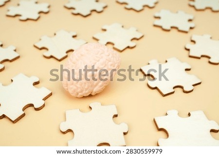 Human brain model surrounded by scattered puzzle pieces, representing problem solving, cognitive function, memory, psychology, intelligence and mental challenges.