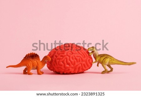 Human brain model with two dinosaurs on pink background. 