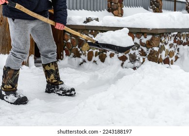 Human cleaning snow with shovel near house. - Shutterstock ID 2243188197