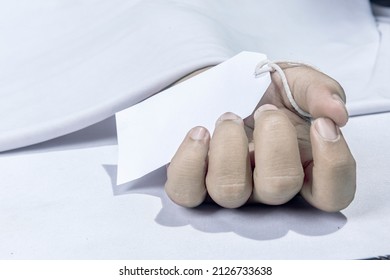 Human corpse covered with a sheet and name tag on hand in the morgue - Shutterstock ID 2126733638