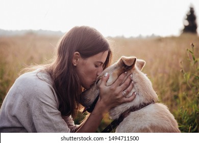 Human and a dog. Girl and her friend dog on the straw field background. Beautiful young woman relaxed and carefree enjoying a summer sunset with her lovely dog