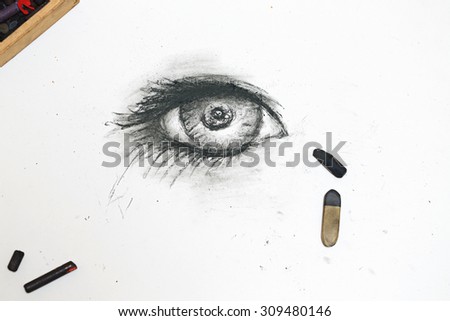 The human eye is drawn in charcoal on paper. The concept of creativity.