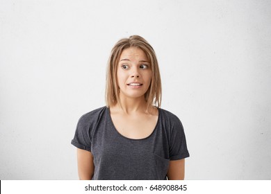 Human facial expressions, emotions, feelings, attitude and reaction. Headshot of funny girl with bob hairstyle looking away, feeling confused, maintaining akward silence in embarrassing situation