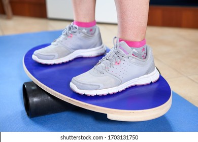 Human Feet In Jogging Shoes Standing On A Balance Board