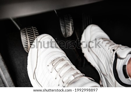Human feet pressing car pedal.