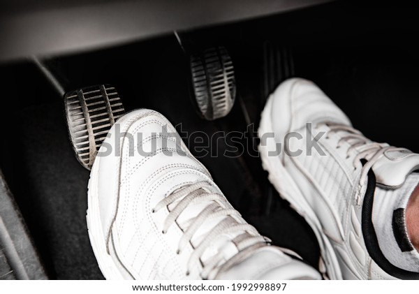 Human feet pressing car\
pedal.