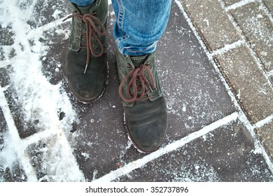 Human Feet Wearing Winter Shoes And Jeans Walking On Slippery Pavement, Overhead Shot With Shallow Depth Of Field