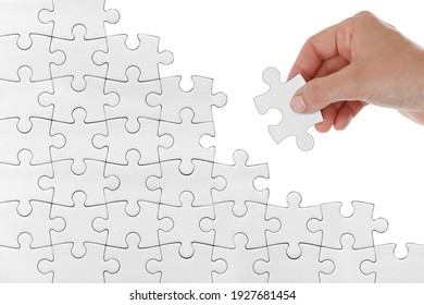
Human female hand trying to connect white puzzle piece isolated on white background. Doing or making a jigsaw puzzle trying connection find solution strategy concept image. reconstruction, rebuilding