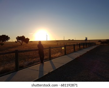 Human Figure In Silhouette At Emu Downs Wind Farm, Western Australia, Waiting And Watching Over Beautiful Orange Sunset