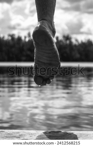 Human foot on water surface in vertical grayscale