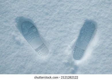 Human Footprints In The Snow Under Sunlight Close-up View. Texture Of Snow Surface, Overhead View.