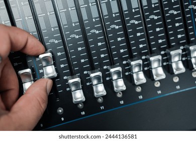 Human hand adjusting buttons on audio mixer. Professional audio mixing console - Powered by Shutterstock