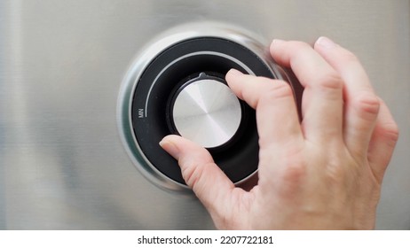 Human Hand Adjusting Power On A Power Regulation Knob Of An Electric Grill