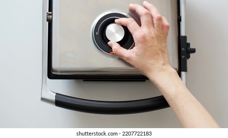 Human Hand Adjusting Power On A Power Regulation Knob Of An Electric Grill