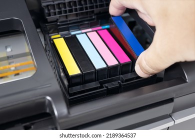 Human hand changing a blue ink cartridge of a multicolor inkjet printer