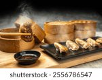 Human hand with chopstick eat fried chinese dim sum dumpling, gyoza, jiaozi or mandu with soy sauce on the table. Food for breakfast, lunch or dinner. Chinese Or Lunar New Year decoration