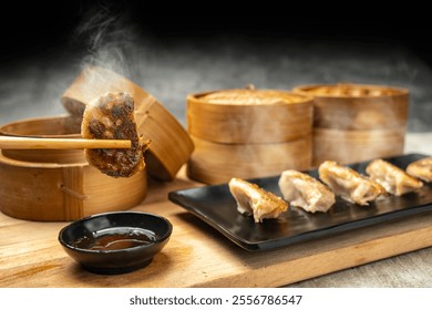 Human hand with chopstick eat fried chinese dim sum dumpling, gyoza, jiaozi or mandu with soy sauce on the table. Food for breakfast, lunch or dinner. Chinese Or Lunar New Year decoration