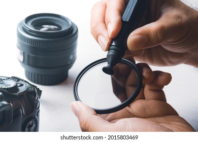 Human hand cleaning stain on CPL filter of camera lens with carbon brush cleaner - Powered by Shutterstock