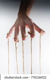 The human hand controls the puppet with the fingers attached to them threads on a white background