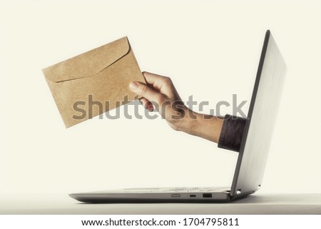 The human hand with envelope stick out of a laptop screen. Concept of correspondence, feedback, advertising via internet.