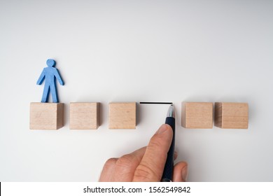 Human Hand Filling Gap Between Wooden Blocks Arranged In A Row With Blue Human Figure