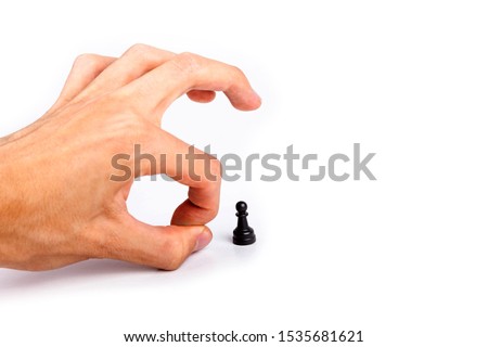 Human hand flicking a chess piece, huge hand flicks away a small tiny black pawn. Flick gesture isolated on white. Danger, anxiety and peer pressure, being fired, losing job due to layoffs concept