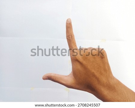 A human hand forms an "L" shape with its thumb and index finger against a plain white background, symbolizing "loser" or a framing gesture.