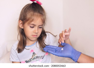 Human Hand Giving Child Medicine Healthcare Pill. The Child Does Not Want To Be Treated And Drink Medication. Ick Girl Takes A White Pill From The Doctor's Hand.