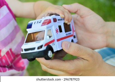 A Human Hand Giving A Toy Car With The Word Emergency Over It It To A Child Demonstrating Concept Of Lifesaving