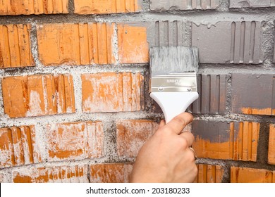 Human Hand With Grey Colored Brush Painting Brick Wall