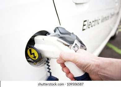 Human Hand Is Holding Electric Car Charging Nozzle. Selective Focus On Hand And Nozzle