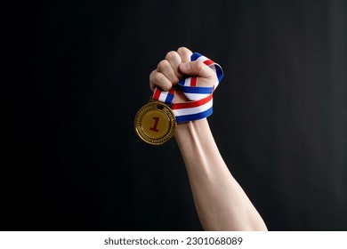 Human hand holding gold medal on black background. - Powered by Shutterstock