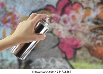 Human Hand Holding A Graffiti Spray Can In Front Of A Colorful Wall