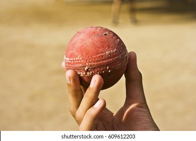 Human Hand Holding Old Cricket Ball.