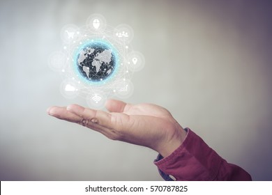 Human hand holding our planet earth glowing with tech icon flow connection concept.
