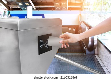 Human Hand Holding Plastic Cards Or Reservations Train Ticket To The City With Escalator Of The Subway Station In Modern Building With Sunshine Background.