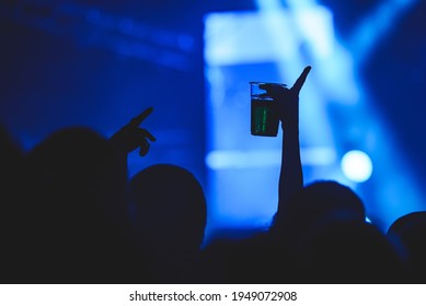 Human Hand Holding A Plastic Cup Full Of Alcohol While In The Air On The Concert Hall