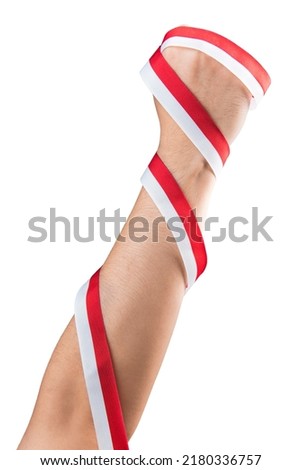 Human hand holding a ribbon with the red and white color of the Indonesian flag isolated over white background