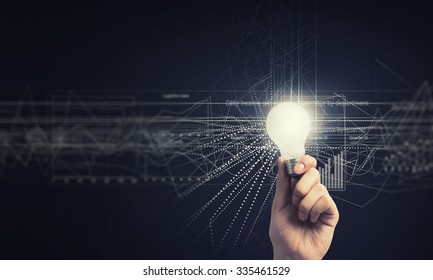 Human hand holding shining electric bulb and infographs on wall
