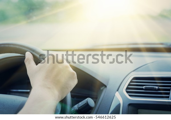 Human\
hand holding the steering wheel in the car.\
Toned
