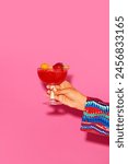 Human hand holding sweet and sour fruity cocktail with berries against pink background. Concept of alcohol and non-alcohol drink, party, holidays, bar, mix. Poster. Copy space for ad