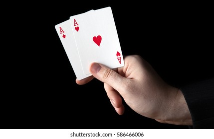 human hand holding two aces on a black background