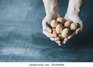 Human Hand Holding Walnuts On Dark Blue Background