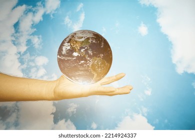 Human Hand Holding The World Earth Above Blue Natural Background. Safe World Concept.. Safe World Concept. Elements Of This Image Furnished By NASA