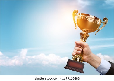 The human hand holds the champion golden trophy. Success concept.