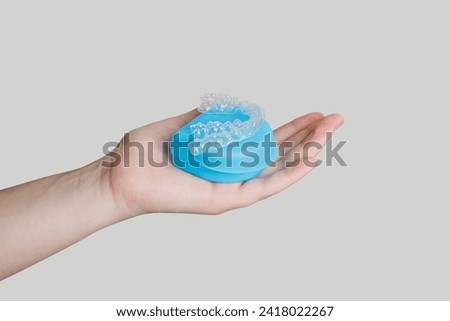 Human hand holds invisible aligners plastic braces dentistry retainers to straighten teeth on white background