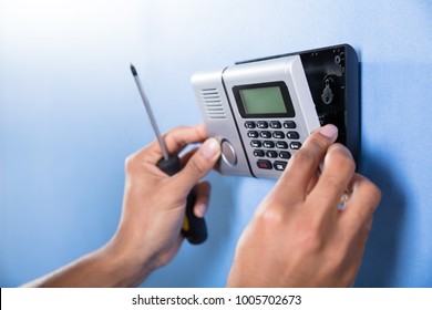 Human Hand Installing Security System On Blue Wall