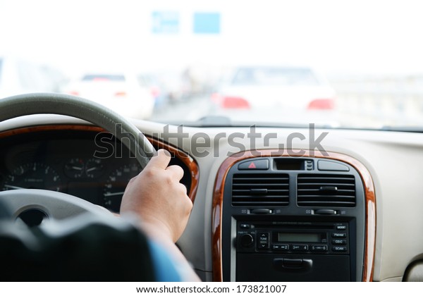 Human hand on\
steering wheel inside of a\
car.