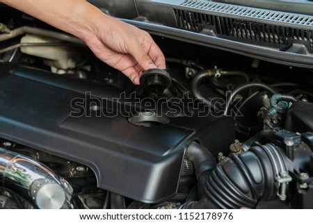 Human hand is opening the car engine oil cap to check the machine